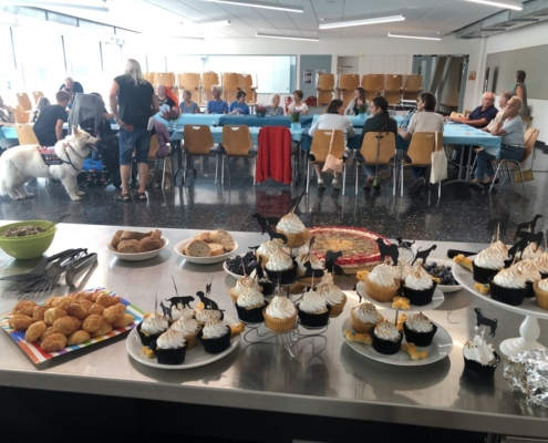 Vue sur un buffet sucré et salé devant des convives réunis autour de tables bleues lors des 20 ans de L'Association L'Autre Regard.