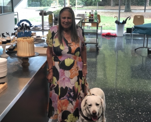 Une dame souriante aux côtés de son chien guide labrador, lors du 20ème anniversaire de l'Association L'Autre Regard.