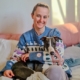 Jeune dame souriante, assise sur un canapé et tenant Charlie, lévrier whippet, dans ses bras.