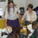 Deux dames accompagnées de leurs chiens d’assistance se rencontrent lors d’un événement, souriantes et entourées de stands.