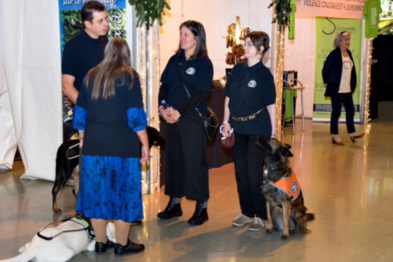 Échange entre membres de l'association L'Autre Regard, accompagnés de chiens d’assistance, lors d’un événement.